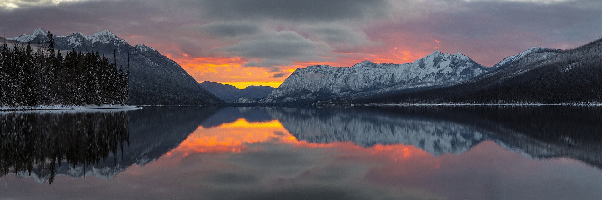 lake with sunrise, sunrise also reflected in lake mountains meet the lake red, yellow and gray hues